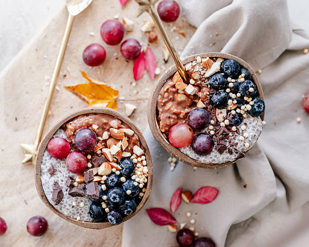istock Two small oatmeal and chia pudding bowls with grapes, berries, almonds and chocolate 2212047132