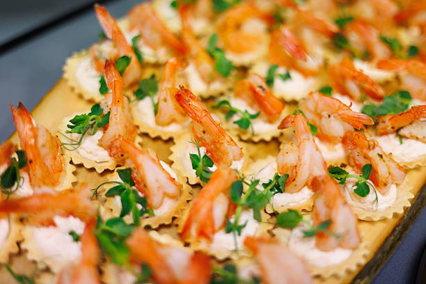 Succulent shrimp served on crispy crackers with a creamy spread and fresh herbs, making a perfect elegant bite-sized appetizer for parties and celebrations. Shallow lens blur