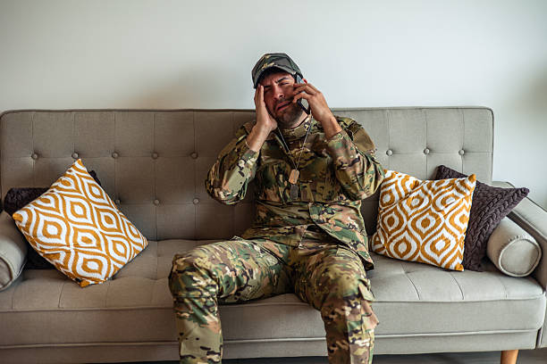 istock Depressed soldier crying while speaking on the phone at home 2212051611