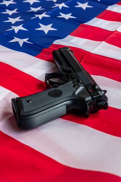 istock Black handgun lying on United States flag raising concerns about gun control 2212051960