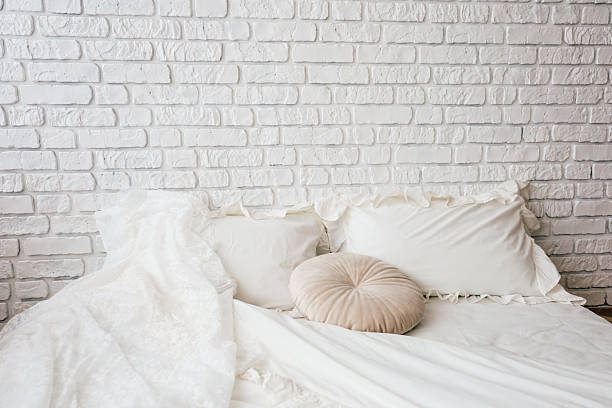 istock Comfortable bedroom setup with white brick wall and soft bedding during daytime 2212053835