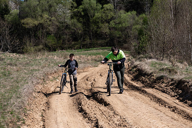 istock Father and son walk their bikes down a dirt path, enjoying a sunny day outdoors. 2212056973