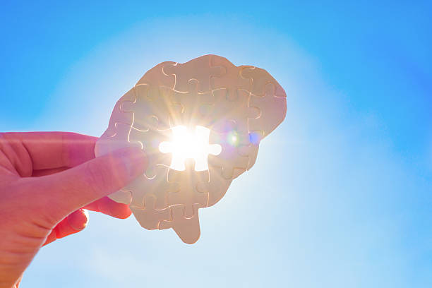 istock Hand Holds Incomplete Brain Shaped Puzzle With Sun Rays Coming Through Against Blue Sky Background 2212058711
