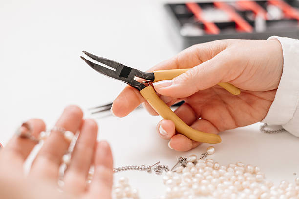 istock Young woman creating DIY jewelry with dried flowers and tools at home workshop table 2212059021