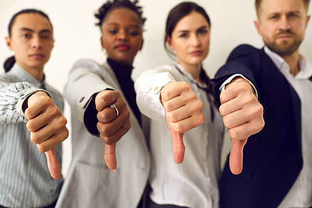 Group of diverse business people giving thumbs down showing dislike of bad work results stock photo