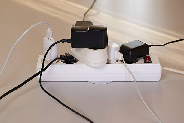 istock Various electrical appliances plugs connected to the white extension cord. Electrical overload. Overloaded power plugs, close up 2212066009