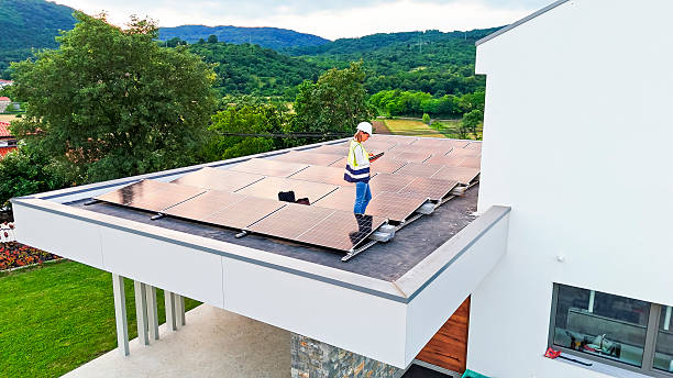 istock Female Technician Programming Solar Panels on Modern Home Roof Amidst Green Hills 2212069144