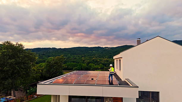 istock Female Technician Programming Solar Panels on Modern House at Sunset with Scenic Green Hills 2212069150