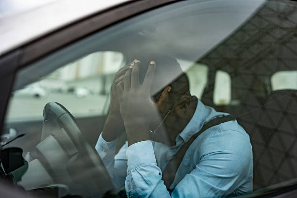 istock Stressed Man Sitting Inside a Car Holding His Head in Frustration 2212069835
