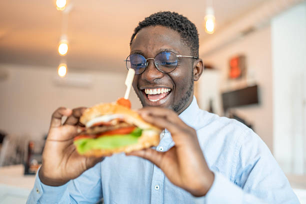 istock Smiling Man Enjoying a Delicious Burger in a Casual Dining Setting 2212070235
