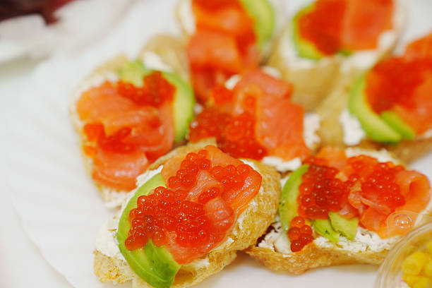 Sandwiches with avocado, red fish and caviar. A delicious gourmet snack with seafood.