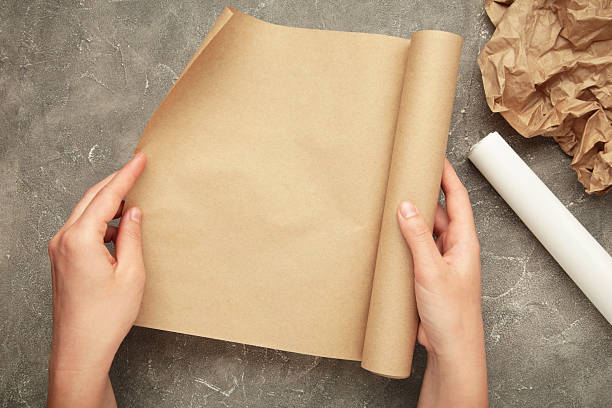 istock Female hands with roll of baking paper on grey concrete background 2212071641