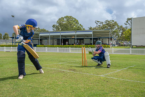 Young male wicketkeeper catching the ball on the field.