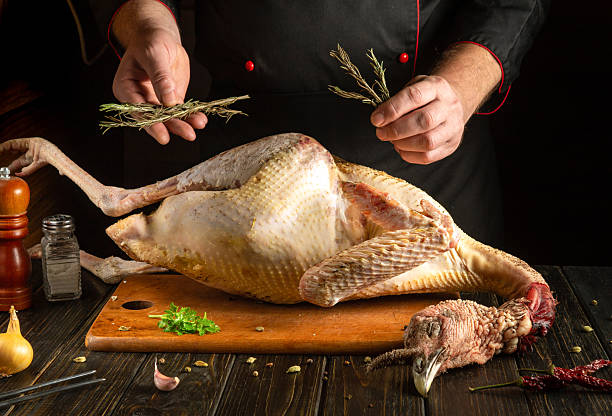 istock A chef in a rustic kitchen prepares a turkey for cooking, skillfully adding fresh herbs to enhance flavor. The atmosphere is warm and inviting, evoking a sense of tradition 2212077202