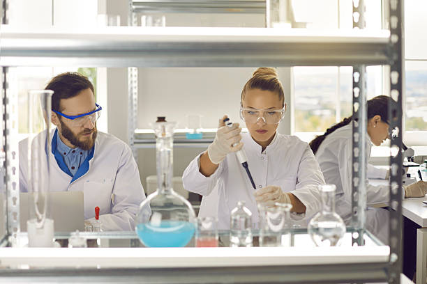 istock Young female scientist taking sample with pipette standing at worktable 2212077866