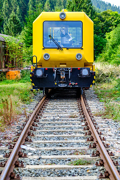 istock Yellow railway maintenance vehicle on tracks surrounded by greenery in a forested area during the day 2212077972