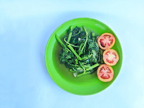 Spinach dish on a plate with three slices of tomato