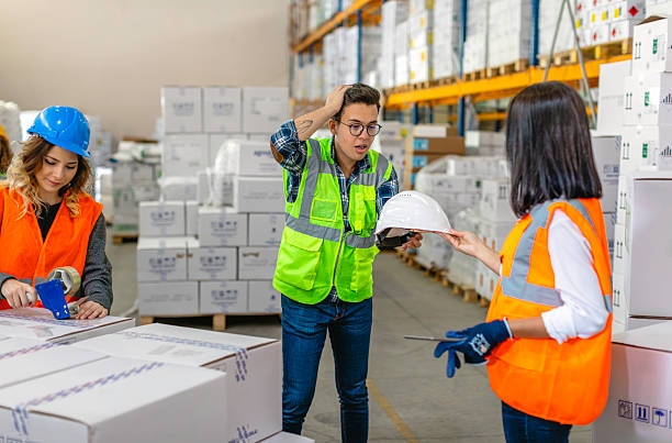 istock Warehouse Workers in Safety Gear Discussing and Handling Boxes in a Warehouse 2212081790