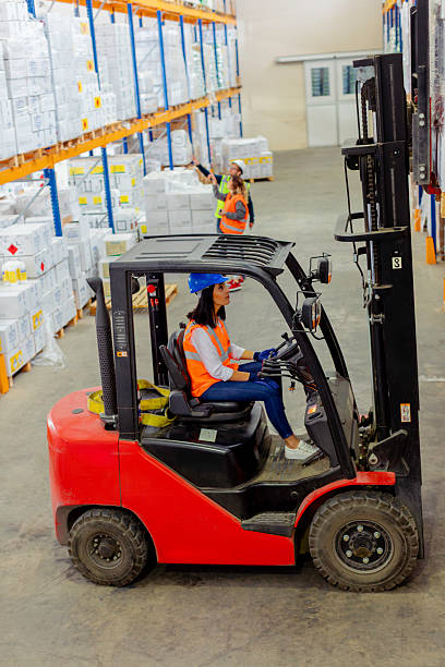 istock Female Forklift Operator Driving Forklift in a Warehouse with Another Worker in the Background 2212081800