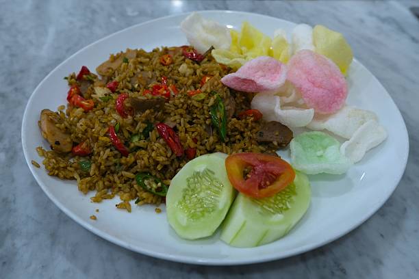 Top view of Indonesian fried rice or nasi goreng served with colorful crackers, cucumber, tomato slices