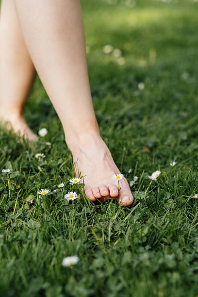 istock Overstimulation: How To Handle Sensory Overload. A close-up of bare foot touching green grass with delicate daisy flower, moment of connection with nature to counter sensory overload. 2212089741