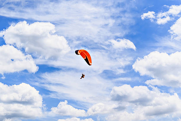 Paragliding adventure with a red and blue parachute on a sunny day.