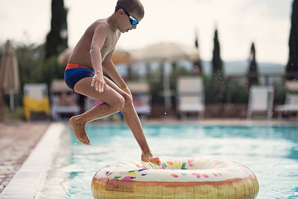istock Little boy jumping into the float in the swimming pool. 2212092095