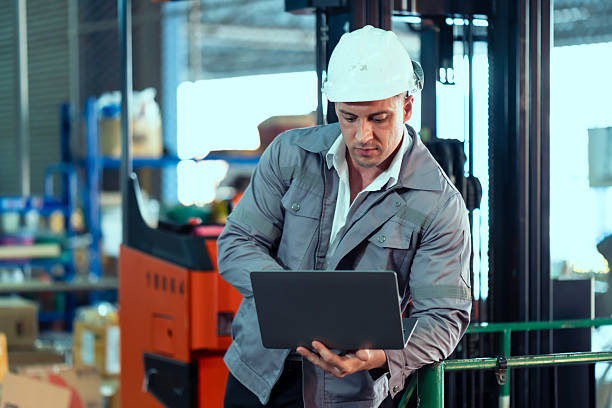 istock Warehouse male worker wearing helmet using laptop analyzing logistics data for warehouse management planning inventory control supply chain efficiency teamwork symbolizing industrial operation 2212093288
