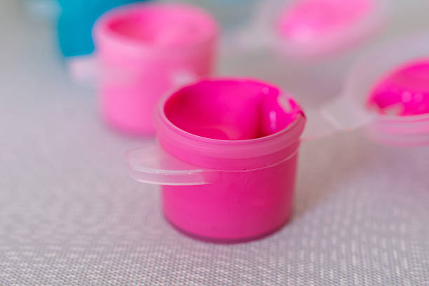 istock Pink paint container with a lid on a table. The lid is white and has a pink handle. 2212093744