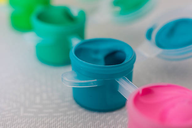 istock Blue paint container with a white lid. The lid has a white handle. There are other containers of paint in the background. 2212093781