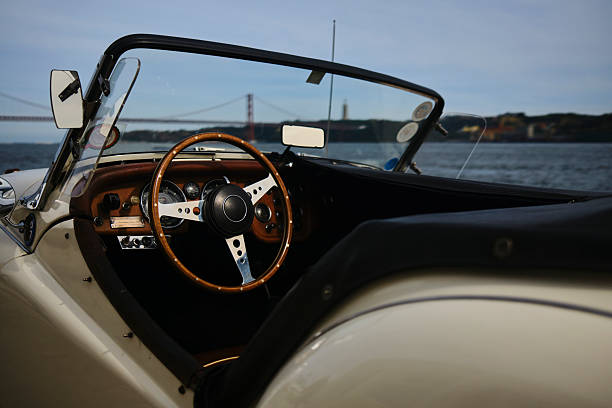Vintage, luxury, convertible car parked on riverbank, 25 of April Bridge in distance, Lisbon