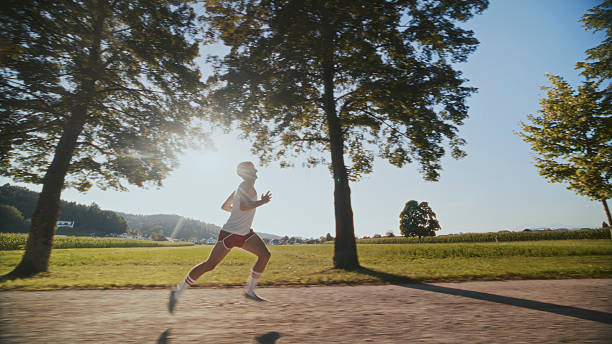 istock Retro-Clad Man Running Outdoors Under Bright Sunlight in a Scenic Park 2212094679