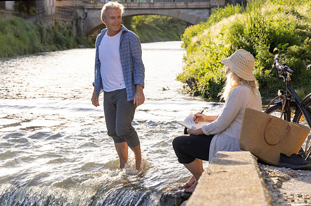 Mature couple relax on riverbank in springtime