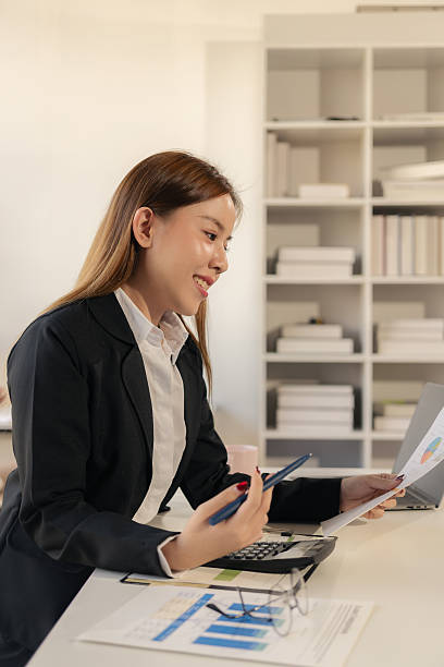 istock Young Asian accountant working with financial documents, analyzing finances, doing company accounting. 2212095759
