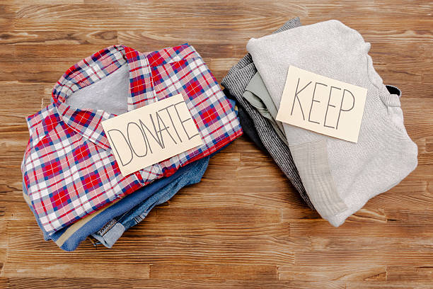 istock Stack of old baby children clothes sorted into Keep and Donate categories.Donation,volunteering help,humanitarian aid.charity on wooden background still life.Recycle clothing,eco cotton 2212101625
