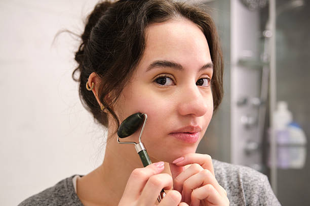 istock Young Woman Using a Jade Roller for Facial Massage in the Bathroom 2212103174