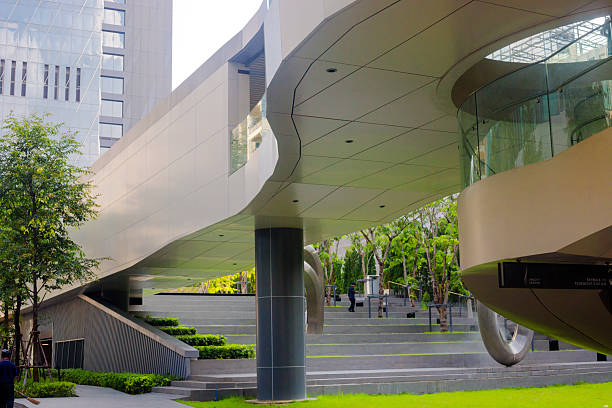 Futuristic designed footbridge and steps below in front of OCC - One City Centre at Phloen Chit Road in Bangkok Lumpini. In left backgrund is tower building. A few people afre walking down the steps. Footbridge is connected to BTS skytrain footbridge