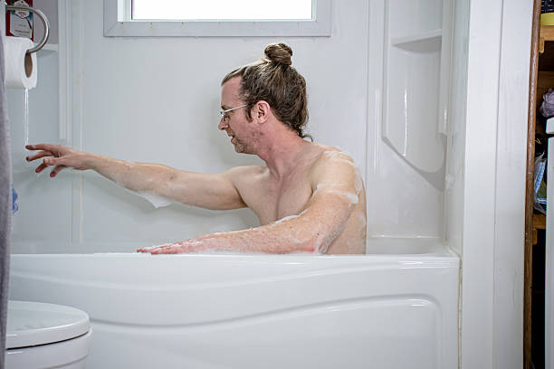 istock Autistic Man Reaching for Faucet in Calming Bath Routine 2212115136