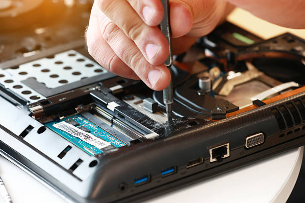 istock Repaiman with screwdriver fixing disassembled laptop parts. Technical support and fixing gadgets problems. Servicing, repairing, cleaning, maintaining computers. Repair shop. Hardware maintenanc 2212116538