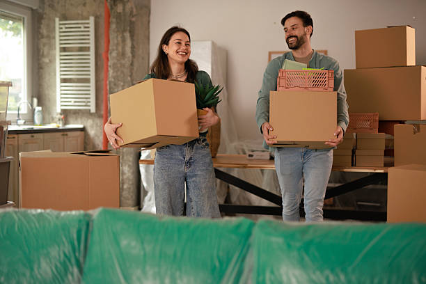 istock Young couple carrying cardboard boxes while moving into new home 2212119080