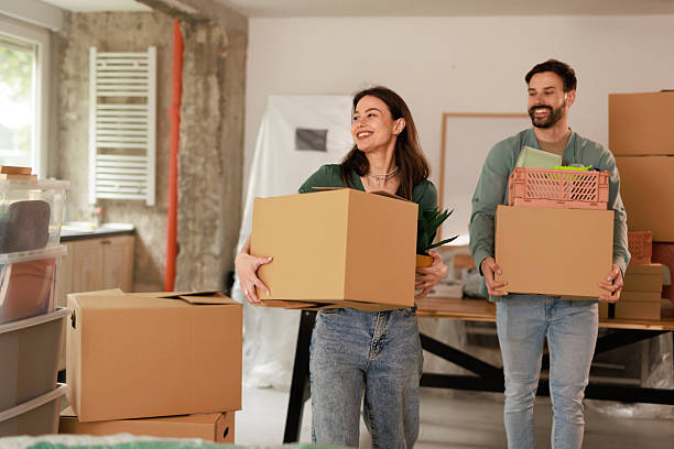 istock Young couple carrying cardboard boxes while moving into new apartment 2212119106