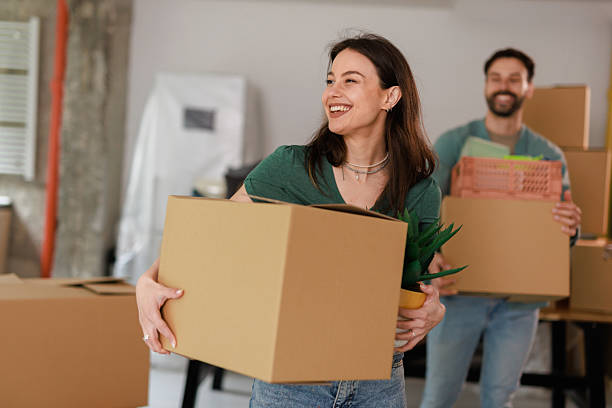 istock Young couple carrying boxes and smiling while moving into new apartment 2212119178