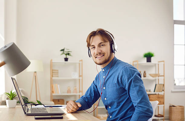 istock Happy young man using laptop computer and headphones and enjoying online education 2212119278