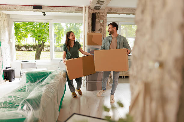 istock Young couple carrying cardboard boxes while moving into new home 2212120268