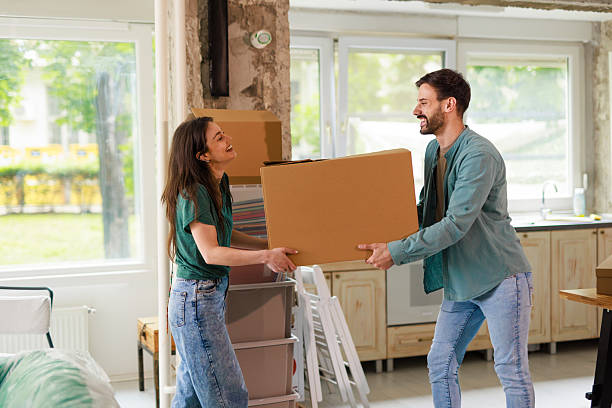 istock Young couple carrying cardboard box while moving into new apartment 2212120360