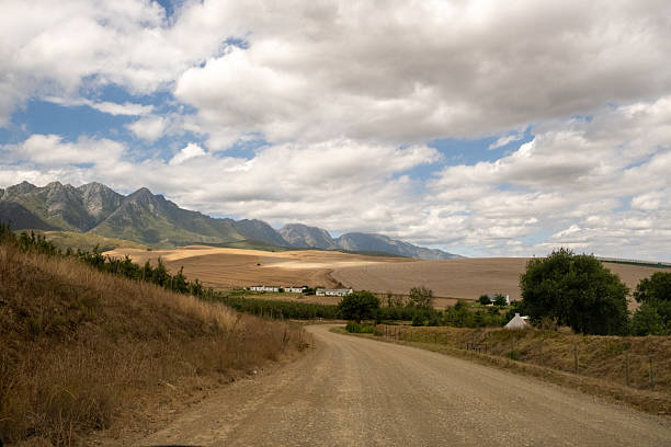 Rustic landscapes and rural life scenes in South Africa, featuring open farmland, sheep herds, mountain ranges, remote villages, and scenic roads under dramatic skies.