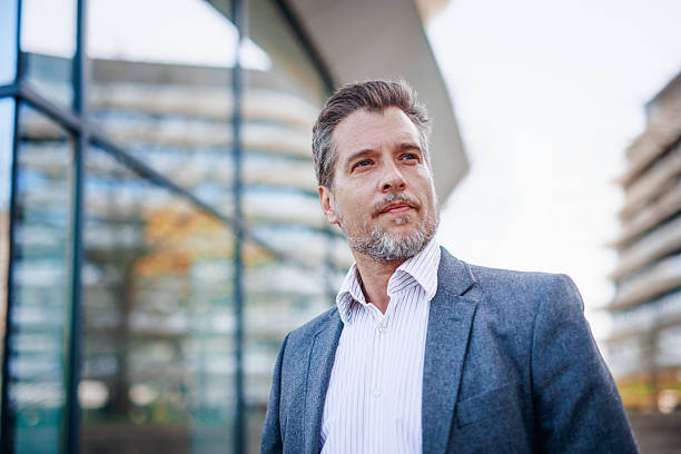 istock Confident businessman looking away while standing near office buildings 2212122826
