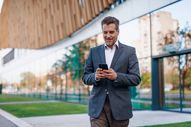 istock Businessman walking and using smartphone near modern office building 2212122840