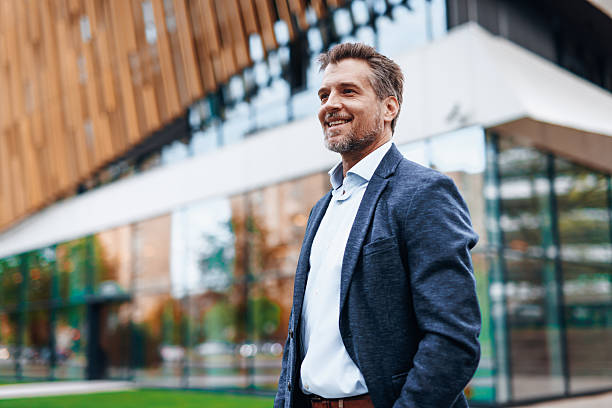 istock Smiling businessman standing in front of modern office building 2212122915