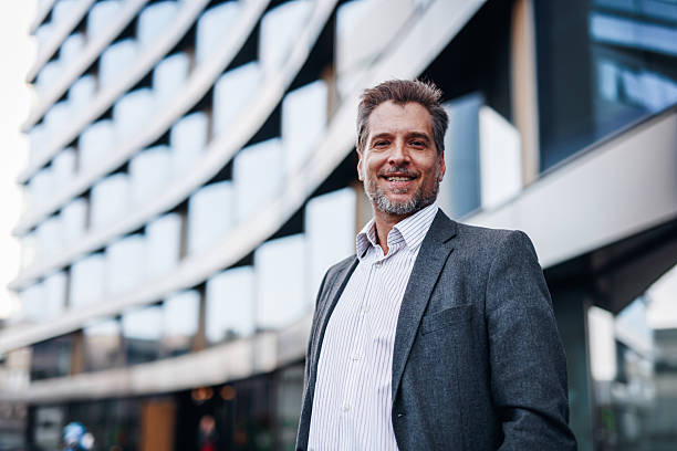 istock Smiling businessman standing in front of modern office building 2212123388
